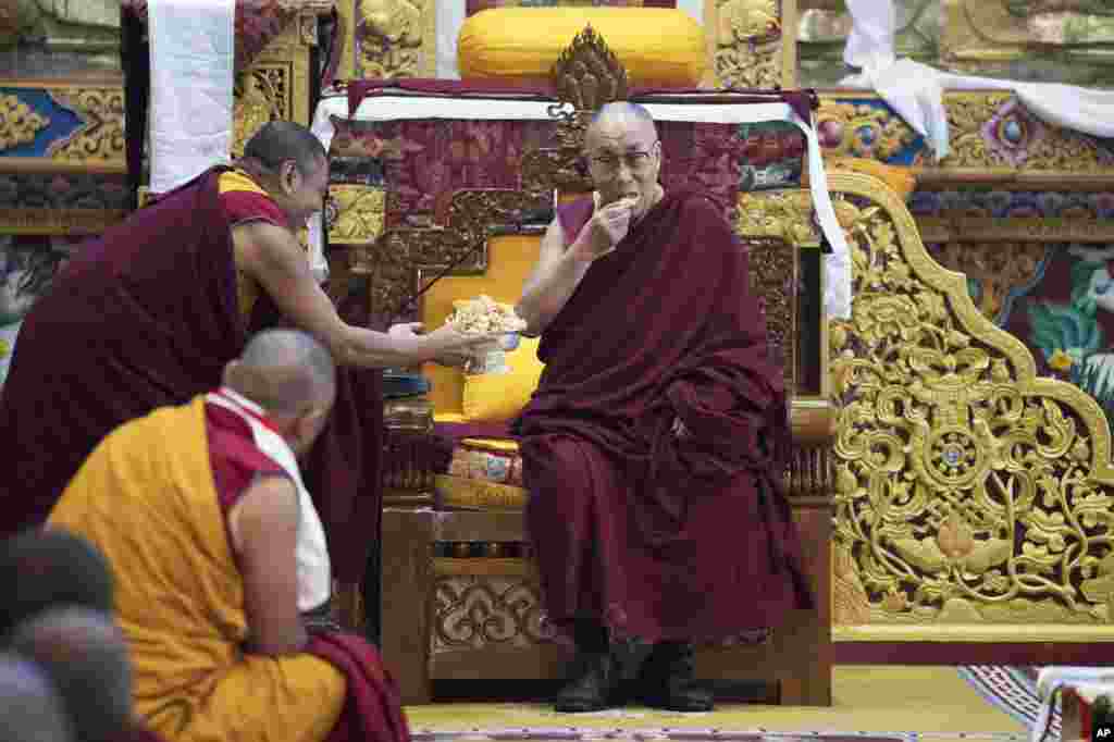 دالایی لاما رهبر معنوی بوداییان تبت در حال خوردن شیرینی سنتی تبت در معبدی در هندوستان