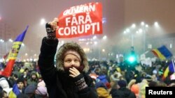 FILE - A woman holds up a sign that reads "government without corruption" during a demonstration of thousands of Romanians against their government in Bucharest, Romania, Feb. 6, 2017. 