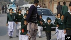 Petugas keamanan mengamankan murid-murid sekolah di dekat sekolah yang diserang militan Taliban di kota Peshawar, Pakistan (16/12).