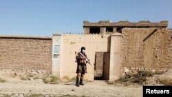 FILE - A Taliban solider stands guard in front of a house neighboring an Islamic State hideout raided by Taliban forces in northern Kabul, Afghanistan Oct. 4, 2021.