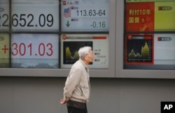 A man walks by an electronic stock board of a securities firm in Tokyo, Monday, Dec. 3, 2018. Shares are advancing in Asia following the meeting between Presidents Donald Trump and Xi Jinping.