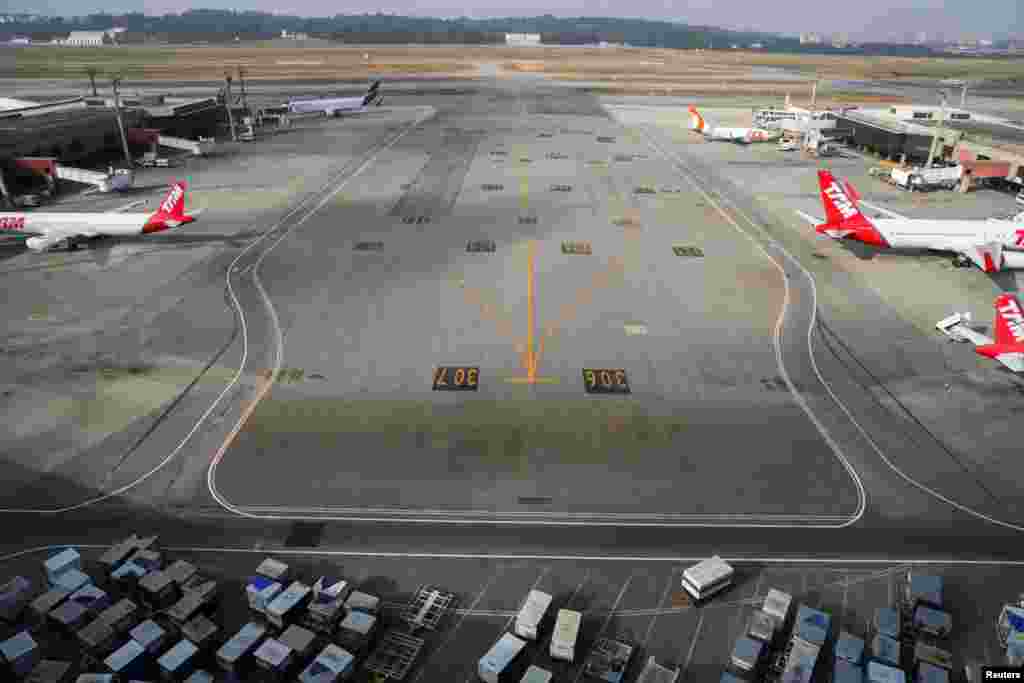 برازیل کے ساؤ پولو ایئرپورٹ پر کھڑے طیارے اور مسافروں کا سامنا جہاز تک لے جانے والے لگیچ کارٹس۔ &nbsp; &nbsp; 