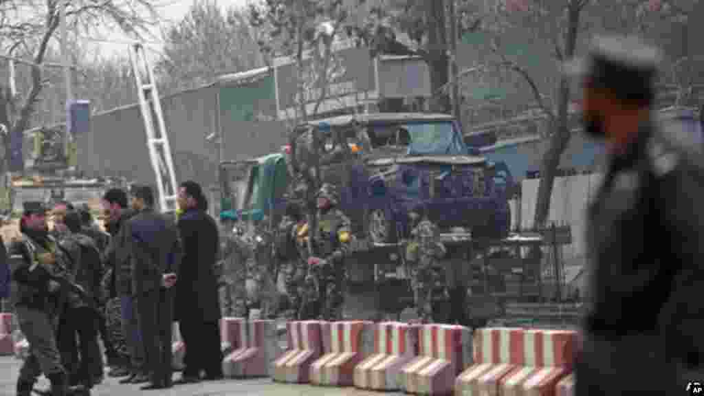 Turkish and Afghan security personnel inspect a damaged vehicle at the site of a suicide attack in Kabul, Feb. 26, 2015.