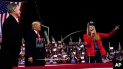 FILE - In this Dec. 5, 2020, file photo Georgia Senator Kelly Loeffler speaks as President Donald Trump and Georgia Senator David Perdue listen at a campaign rally at Valdosta Regional Airport, Dec. 5, 2020, in Valdosta, Georgia.