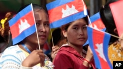 Garment workers welcome Prime Minister Hun Sen outside of Phnom Penh, Cambodia, Wednesday, Aug. 30, 2017. Hun Sen is on a country-wide trip to visit the nation's factory workers to hear their hopes and concerns in person. (AP Photo/Heng Sinith)