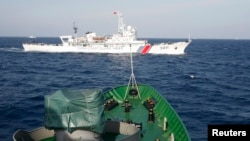 一艘中国海岸警卫队的船只（上）2014年5月14日在越南海岸外210公里处游弋