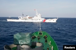 FILE - A Chinese Coast Guard ship (top) is seen near a Vietnam Marine Guard vessel in the South China Sea, about 210 km (130 miles) off shore of Vietnam, May 14, 2014.