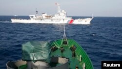 Sebuah kapal China (atas) tampak berlayar dekat kapal AL Vietnam di Laut China Selatan (foto: ilustrasi).