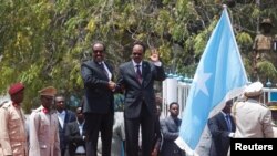 Somalia's newly elected President Mohamed Abdullahi Mohamed (right) flanked by outgoing president Hassan Sheikh Mohamud (left) attends a military parade during the hand-over ceremony at the Presidential palace in Somalia's capital Mogadishu, Feb. 16, 2017