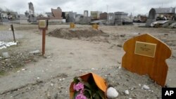 FILE- A bouquet of flower lies on the tomb of Yasser Abdallah, from Sudan, who died in an attempt to cross the English Channel in a truck, Sept. 28, 2021, in the Nord Cemetery of Calais, northern France, Nov. 25, 2021.