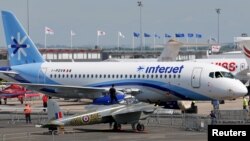 FILE - Workers move a Russia-made Sukhoi Superjet 100 during the Paris Air Show, June 13, 2015. 