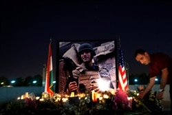 FILE - A man lays flowers next to a photograph of James Foley, the freelance journalist killed by the IS group, during a memorial service in Irbil, 350 kilometers (220 miles) north of Baghdad, Iraq, Aug. 24, 2014.