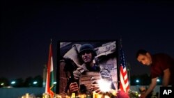 FILE - A man lays flowers next to a photo of James Foley, the freelance journalist killed by the Islamic State group, during a memorial service in Irbil, Iraq, Aug. 24, 2014.