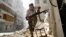 FILE - A Free Syrian Army fighter takes cover during clashes with the Syrian Army.