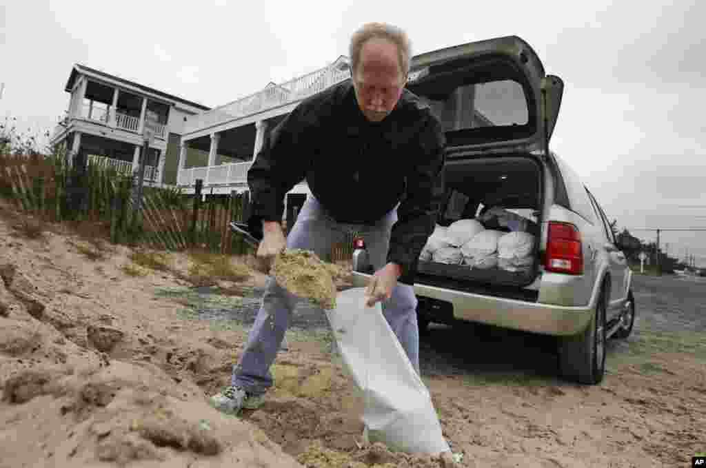 Mike Strobel mengisi karung dengan pasir untuk melindungi bisnis karpetnya, seiring tibanya Badai Sandy di Fenwick Island, Delaware (28/10).