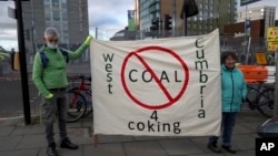 Protesters hold a banner against mining coking coal in the West Cumbria area of northern England, as they stand near the Scottish Event Campus, the venue for the COP26 U.N. Climate Summit in Glasgow, Scotland, Nov. 2, 2021.