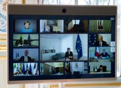 FILE - Members of the European Council are seen on the screen during a video conference call at the Elysee Palace in Paris, March 26, 2020.
