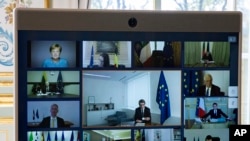 FILE - Members of the European Council are seen on the screen during a video conference call at the Elysee Palace in Paris, March, 26 2020. 