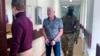 FILE - In this photo taken from video provided by Lefortovo District Court, Robert Shonov, a Russian national who worked at the now-closed U.S. consulate in Vladivostok, is escorted by officers to the courtroom at the Lefortovo District Court in Moscow on May 18, 2023.