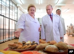 Russian President Vladimir Putin, right, looks at bread and confectionery during his visit to the Samara bakery and confectionery factory on the eve of International Women's Day in Samara, Russia, March 7, 2018.