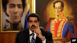 Between two portraits of Venezuela's hero Simon Bolivar in the background, President Nicolas Maduro speaks during a press conference in Caracas, Dec. 30, 2014.