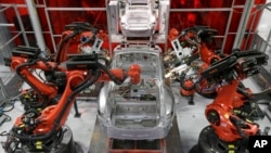 Kuka robots work on Tesla Model S cars in the Tesla factory in Fremont, Calif., Thursday, May 14, 2015. (AP Photo/Jeff Chiu)