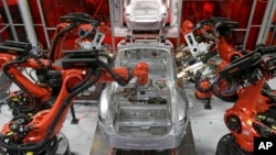 Kuka robots work on Tesla Model S cars in the Tesla factory in Fremont, Calif., Thursday, May 14, 2015. (AP Photo/Jeff Chiu)