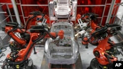 Kuka robots work on Tesla Model S cars in the Tesla factory in Fremont, Calif., Thursday, May 14, 2015. (AP Photo/Jeff Chiu)