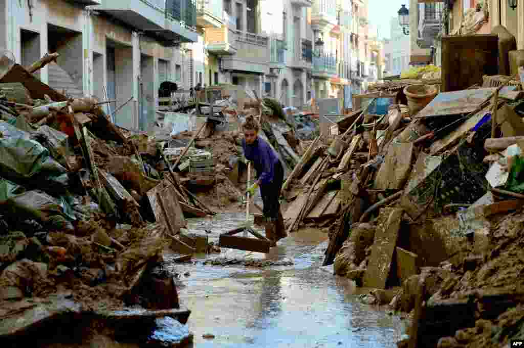 A woman cleans mud among debris in a street of Paiporta, south of Valencia, eastern Spain, in the aftermath of deadly floods.&nbsp;Spain announced an aid package worth 10.6 billion euros ($11.5 billion) to rebuild regions devastated by its worst floods in a generation that have killed 219 people.