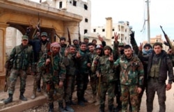 In this photo released Sunday, Feb. 16, 2020 by the Syrian official news agency SANA, Syrian army soldiers flash the victory sign in the Rashideen neighborhood, in Aleppo province, Syria.