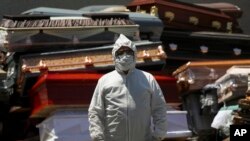An employee of Xochimilco's crematorium waits for a corpse, suspected to have died of the new coronavirus, in Mexico City, May 4, 2020. He is standing next to pile of discarded coffins that contained people who died of COVID-19 disease.