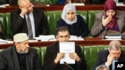 A member of Tunisia's parliament holds up a copy of a document that reads in Arabic "Draft Constitution of the Republic of Tunisia,"Jan. 3, 2014 in Tunis.