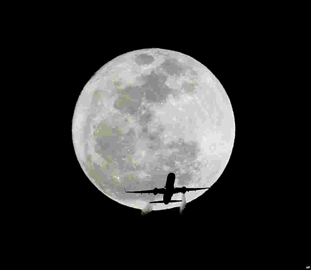 A commercial airliner&#39;s schlieren can be seen while crossing the full moon, or Hunger Moon, over Whittier, California, on its final approach to LAX, Feb. 14, 2014. 