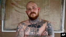Shane Johnson displays some of his tattoos as he poses in his home in Tippecanoe, Indiana, Jan. 12, 2017. Johnson who was born into extremism is in the process of covering some of his racist tattoos with new ones and wears long sleeves to hide remnants of the past he regrets. His father and many of his father's relatives were part of the Klan, he said, so there was only one real way for him to go as a youth.