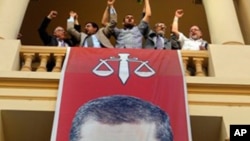 Egyptian campaign officials of the Muslim Brotherhood's candidate, Mohammed Morsi, celebrate over a giant poster of him at his campaign headquarters in Cairo, Egypt, Sunday, June 24, 2012. 