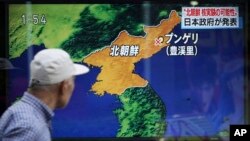 Seorang pria d berjalan melewati layar TV yang sedang menyiarkan berita mengenai kemungkinan tes nuklir Korea Utara, Tokyo, 3 September 2017.