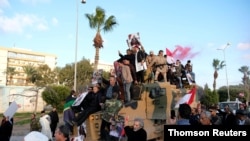 FILE PHOTO: Supporters of Libyan National Army (LNA) commanded by Khalifa Haftar, celebrate on top of a Turkish military armored vehicle, which LNA said they confiscated during Tripoli clashes, in Benghazi, June 7, 2020.