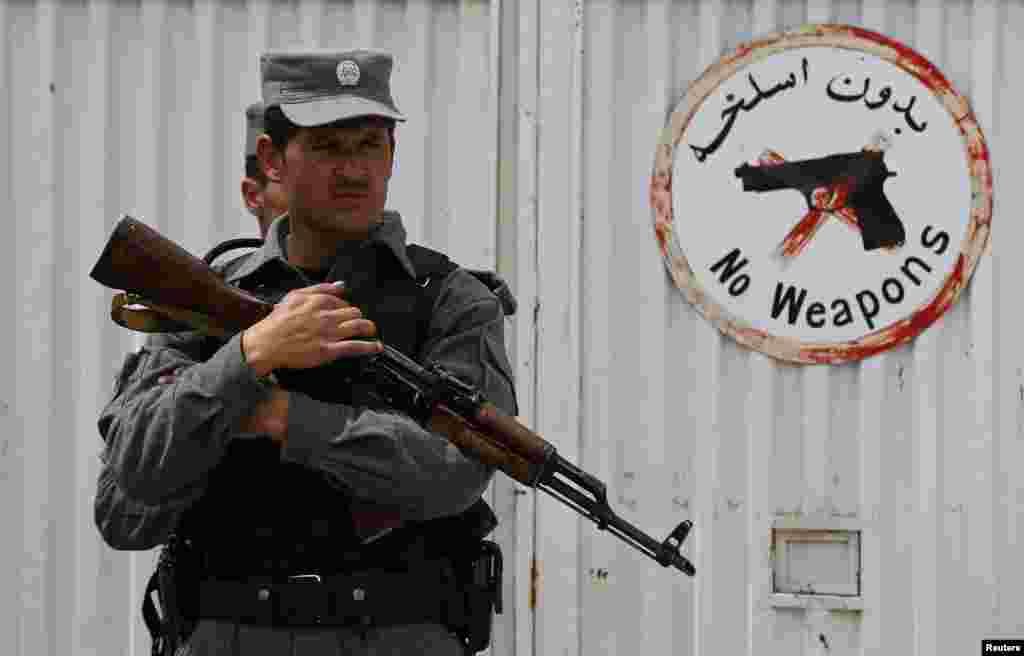 An Afghan police officer stands at the gate of Cure Hospital after three Americans were killed, Kabul, April 24, 2014.