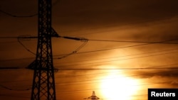 FILE - The sun is seen behind high-voltage power lines and electricity pylons in Bordeaux, France, April 9, 2019. 