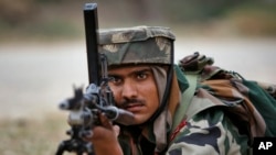 An Indian Army soldier takes position during an encounter with armed suspected militants at Pindi Khattar village in Arnia border sector, 43 kilometers (27 miles) south of Jammu, India, Nov. 27, 2014. 