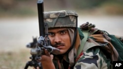 An Indian Army soldier takes position during an encounter with armed suspected militants at Pindi Khattar village in Arnia border sector, 43 kilometers (27 miles) south of Jammu, India, Nov. 27, 2014. 