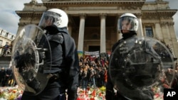 Police in riot gear protect one of the memorials to the victims of the recent Brussels attacks, as right wing demonstrators protest near the Place de la Bourse in Brussels, March, 27, 2016. 