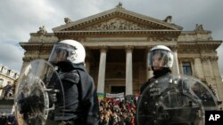 La police anti-émeute patrouille près des manifestants de droite qui protestent sur la Place de la Bourse contre les dernières attaques, à Bruxelles, 27 mars 2016.
