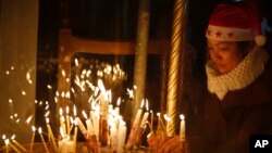 Seorang anggota jemaat menyalakan lilin di Gereja Nativity di Bethlehem, Tepi Barat (24/12). (AP/Majdi Mohammed)