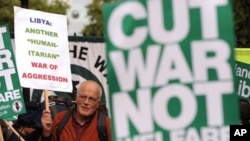 Protesters hold placards as they protest against the British government's involvement in the bombings of Libya, during a demonstration outside Downing street in central London, May 16, 2011