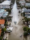 TOPSHOT - In this aerial photo, a vehicle drives though a flooded street after Hurricane Milton, in Siesta Key, Florida, on October 10, 2024.