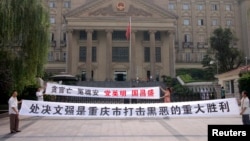 FILE - Residents hold banners outside the high court where Wen Qiang, the former municipal justice chief, was sentenced to death in Chongqing municipality. 