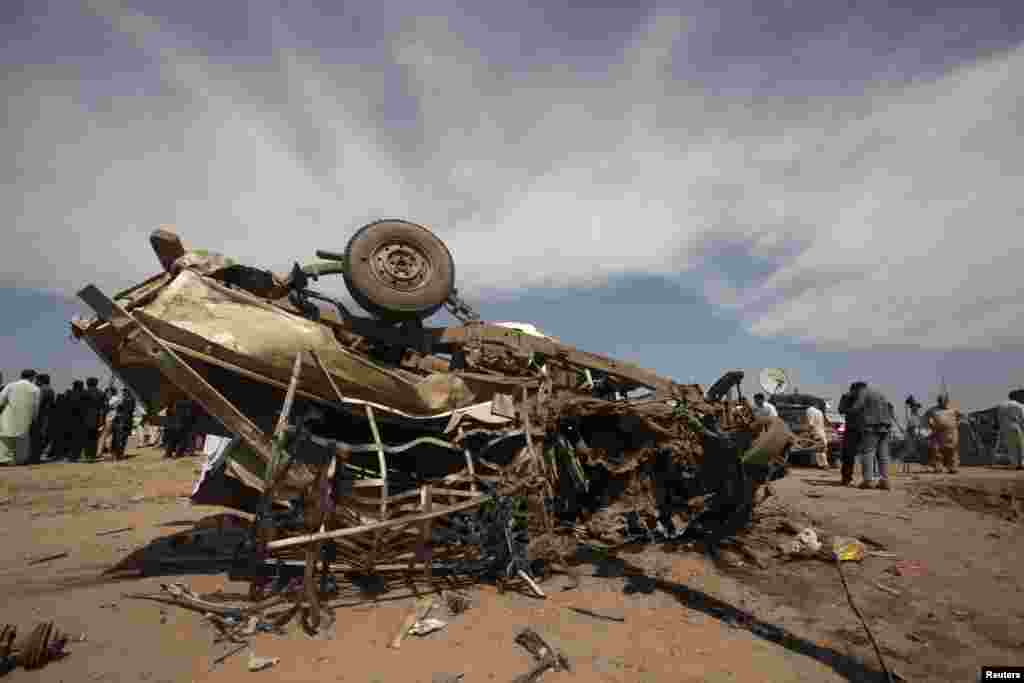 An overturned car is seen at the site of a bomb attack in Jalozai camp in Nowshera district, northwestern Pakistan, March 21, 2013.