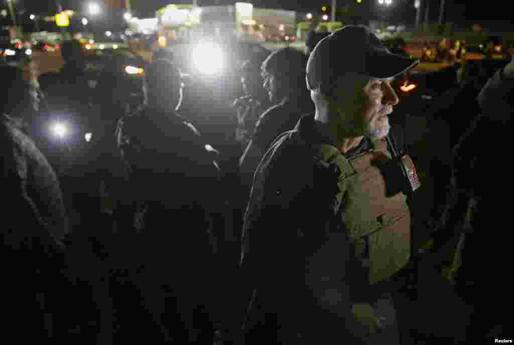 Members of heavily armed civilians talk to members of the media as protesters gather along West Florissant Avenue in Ferguson, Aug. 11, 2015.