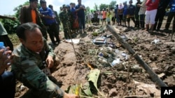 A Lao soldier places incense sticks into the ground beside the wreckage left by a Lao Airlines turboprop plane as he pays his respects to the victims of Wednesday's ill-fated flight, in Pakse, Laos, Oct. 17, 2013.